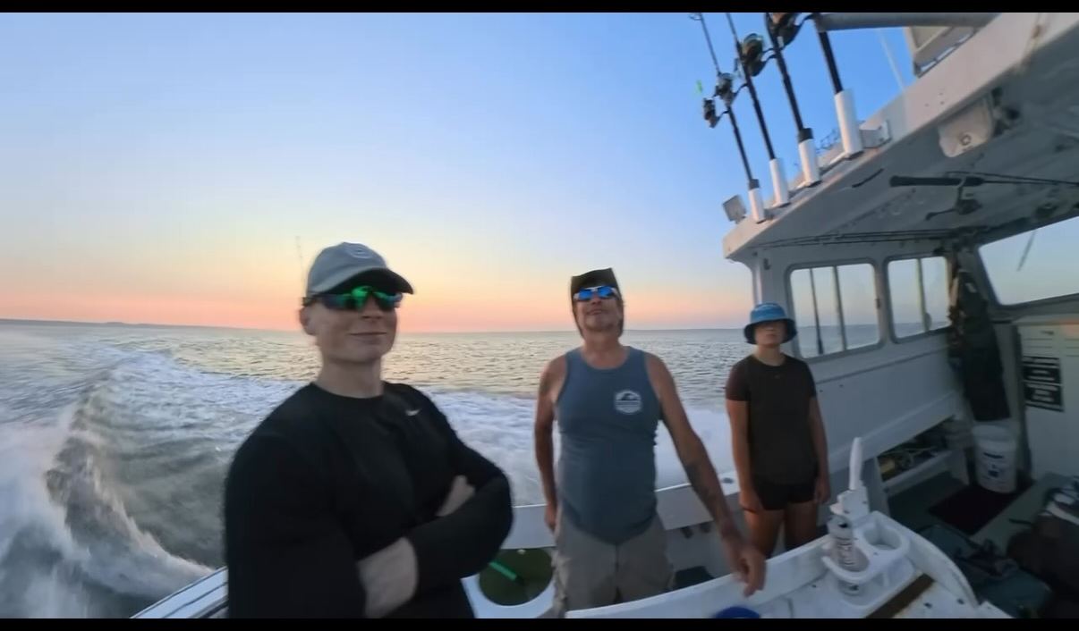 Three anglers on the stern of the boat riding home at sunset